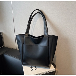 Detail of minimalist black large tote bag with front pocket and matte faux leather texture