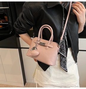 Dettaglio della borsa in pelle rosa chiaro con chiusura a scatto e ciondolo a cuore