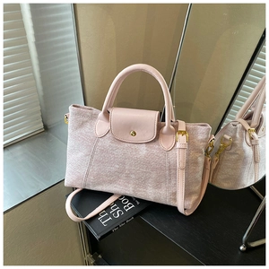 Dettaglio del tessuto rosa con texture a fiocco su una borsa tote con finiture dorate