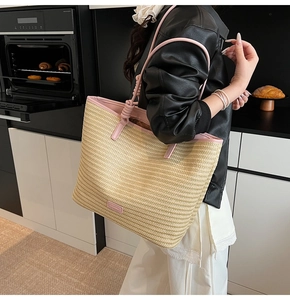 Detail of hand-woven straw tote bag with pink leather handles and side trim design