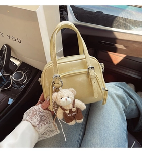 Dettaglio della mini borsa Boston giallo crema con ciondolo orso su un sedile