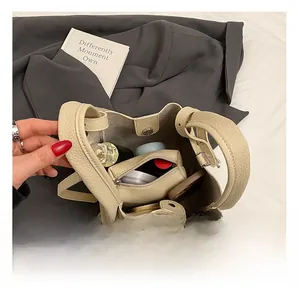 Vista dettagliata della borsa a secchiello crema con spazio interno e pochette zip