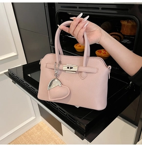 Dettaglio borsa in pelle rosa chiaro con chiusura argento e ciondolo a cuore in ambiente cucina