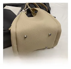 Dettaglio della base della borsa in pelle beige con quattro rivetti protettivi in argento