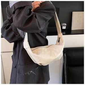 Detail of cream crescent shoulder bag with quilted leather texture and wide strap
