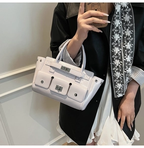 Detail of light colored glossy leather handbag with multi-pockets and silver buckles