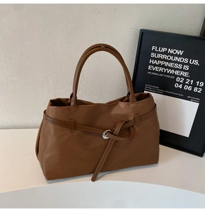 Detailed close-up of the brown tote bag featuring a decorative strap and silver metal buckle