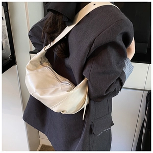 Detail of a creamy white crescent bag showing stitching and adjustable shoulder strap