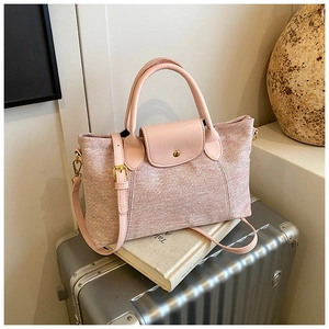 Dettaglio borsa tote rosa in maglia con finiture in pelle e dettagli dorati su valigia
