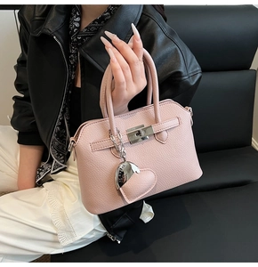 Dettaglio borsa in pelle rosa con chiusura a girello in metallo e ciondolo a cuore