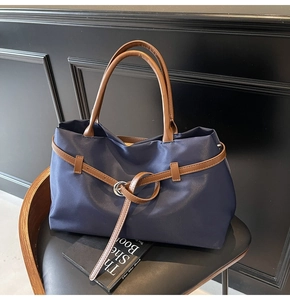 Macro shot of navy nylon tote bag with brown leather straps and silver metal buckles