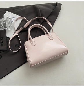 Flat lay of pink leather handbag with top handles and adjustable shoulder strap