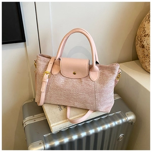 Dettaglio della borsa tote in tela rosa con manici in pelle e fibbia dorata su valigia