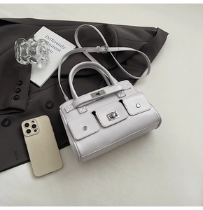 Detail of light gray minimalist crossbody bag with classic twist lock and small pockets