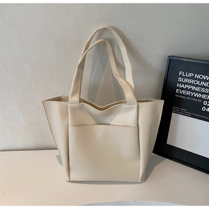 Detail view of cream leather tote bag featuring a functional front pocket and large capacity