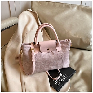 Dettaglio della borsa tote strutturata rosa chiaro con manico in pelle su cappotto beige