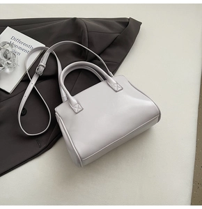 Detail of light grey leather handbag on grey blazer with decorative book and glass art