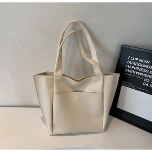 Detail of a large cream tote bag showing fine leather texture and wide front pocket