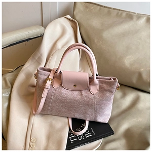 Dettaglio del tessuto rosa a trama fiocco e dei manici in pelle liscia della borsa tote