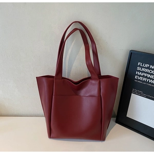 Detailed macro view of the dark red tote bag featuring premium leather texture and stitching