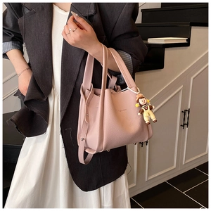 Detail of pink pebbled leather tote bag with FASHION gold stamp and cute boy charm