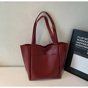 Close-up of burgundy leather tote bag with functional front pocket and sturdy shoulder straps