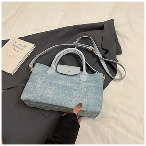 Vista piatta della borsa tote in tela azzurra con tracolla in pelle e chiusura a scatto