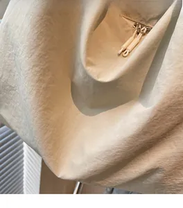 Détail du sac cabas en nylon beige montrant la texture douce et la tirette de zip