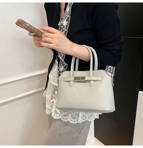 Dettaglio della borsa in pelle grigio chiaro motivo litchi con chiusura a scatto in metallo