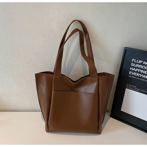Close-up of large brown PU leather tote bag with front pocket and dual straps for women