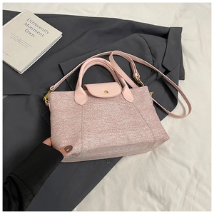 Dettaglio della borsa tote rosa con finiture dorate su sfondo di un blazer grigio scuro