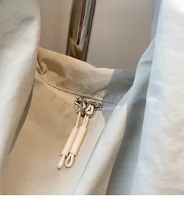 Détail des doubles fermetures éclair en métal et longs cordons sur le sac fourre-tout beige