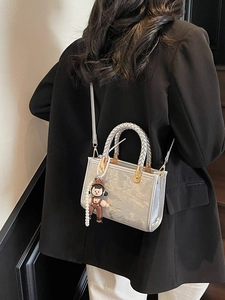 Silver metallic mini crossbody bag with pearl chain and doll charm shown on model