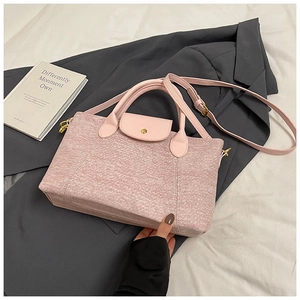 Dettaglio borsa tote in tessuto rosa con manici in pelle e finiture in metallo dorato