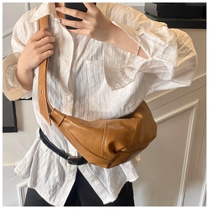 Detail of caramel brown moon bag showing textured leather stitching and wide strap