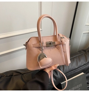 Dettaglio della borsa Kelly in pelle rosa con chiusura a scatto argento e ciondolo a cuore