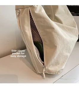 Détail de la poche latérale zippée d'un sac cabas beige montrant la doublure à rayures