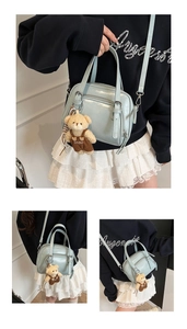 Close-up of light blue glossy patent leather handbag with teddy bear charm and silver hardware