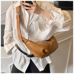Detail of adjustable strap and leather texture on caramel crescent crossbody bag