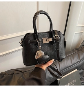 Dettaglio borsa in pelle martellata nera con chiusura a scatto argento e ciondolo a cuore