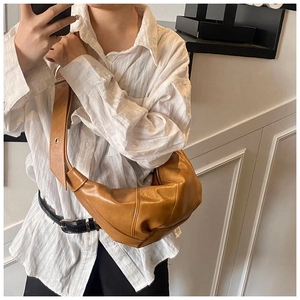 Detail shot of tan croissant bag showing pleated stitching and wide shoulder strap