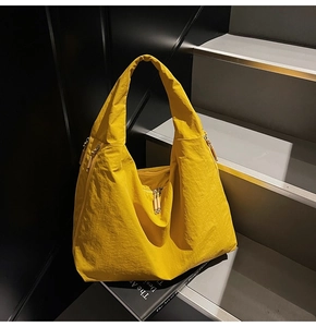Detail of bright yellow tote bag with textured nylon fabric and metallic zipper on stairs
