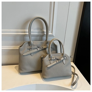 Detail van minimalistische tote bag set met verticale geplooide textuur en zilveren gespen