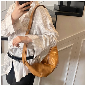 Detail view of the shiny brown crescent bag with adjustable silver buckle strap