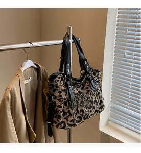 Detail of leopard print tote bag with black leather handles and silver rivets