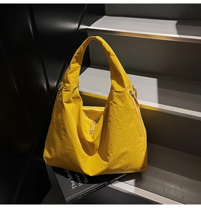 Detail of bright yellow nylon hobo bag featuring natural crinkle texture and metal double zippers