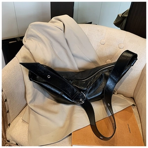 Detail view of a black leather crescent dumpling bag with silver hardware on an armchair