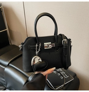 Dettaglio borsa nera con trama litchi, chiusura argento e ciondolo a forma di cuore