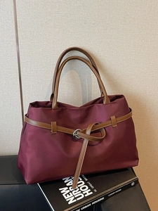 Deep burgundy large nylon tote bag with brown leather handles and decorative buckle strap