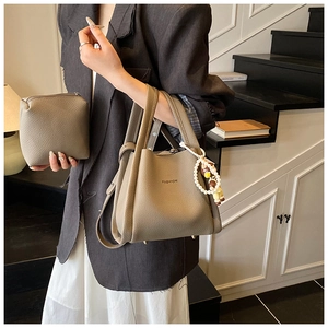 Dettaglio della borsa tote in pelle taupe con scritta FASHION e ciondoli decorativi